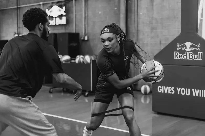 Black-and-white photo of Hannah Hidalgo dribbling past a trainer during a workout