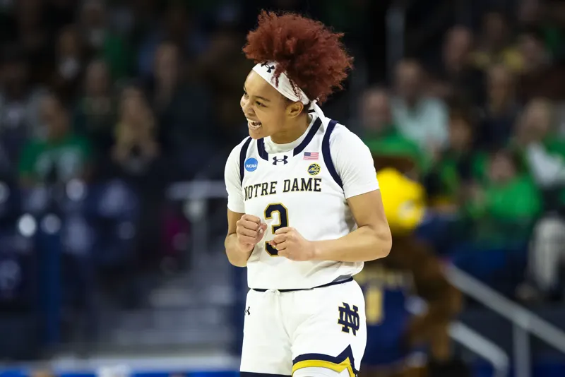 Hannah Hidalgo in a white Notre Dame uniform reacting on the court during a home game