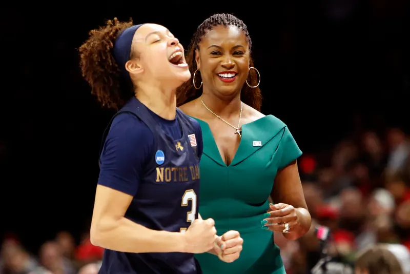 Hannah Hidalgo shouting with joy beside a smiling woman in a green dress after an NCAA Tournament win