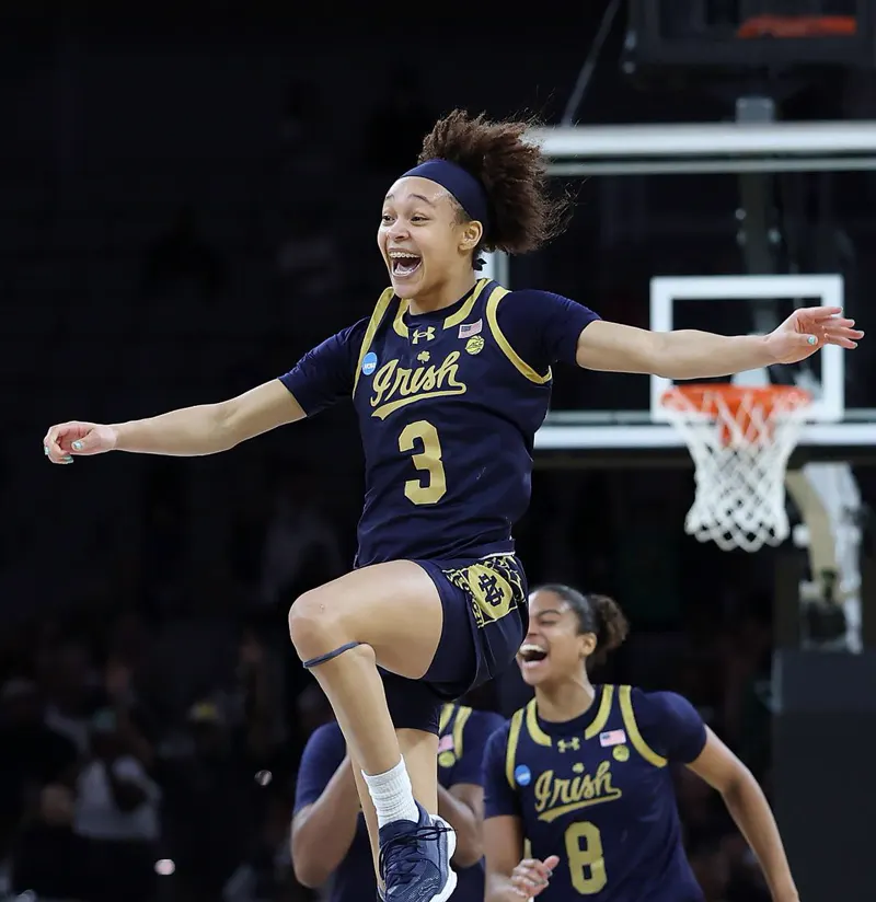 Hannah Hidalgo leaping into the air in celebration as a teammate runs behind her