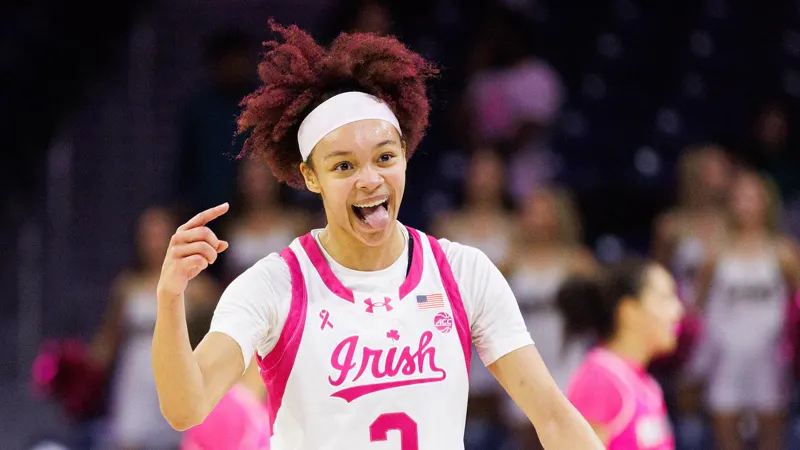 Hannah Hidalgo pointing and grinning in a pink Notre Dame uniform